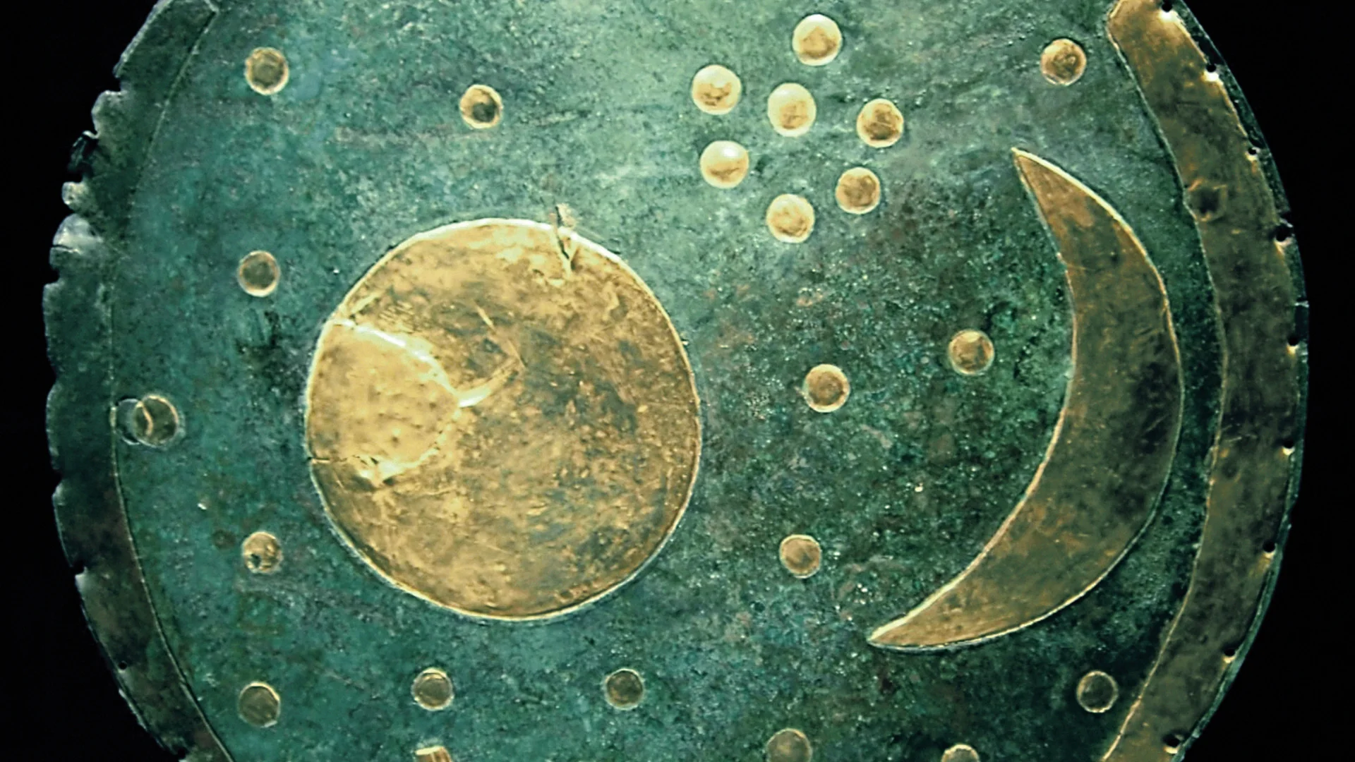 Primary archaeological plate of the Nebra Sky Disk showing gold crescent Moon, star cluster, and horizon arcs.